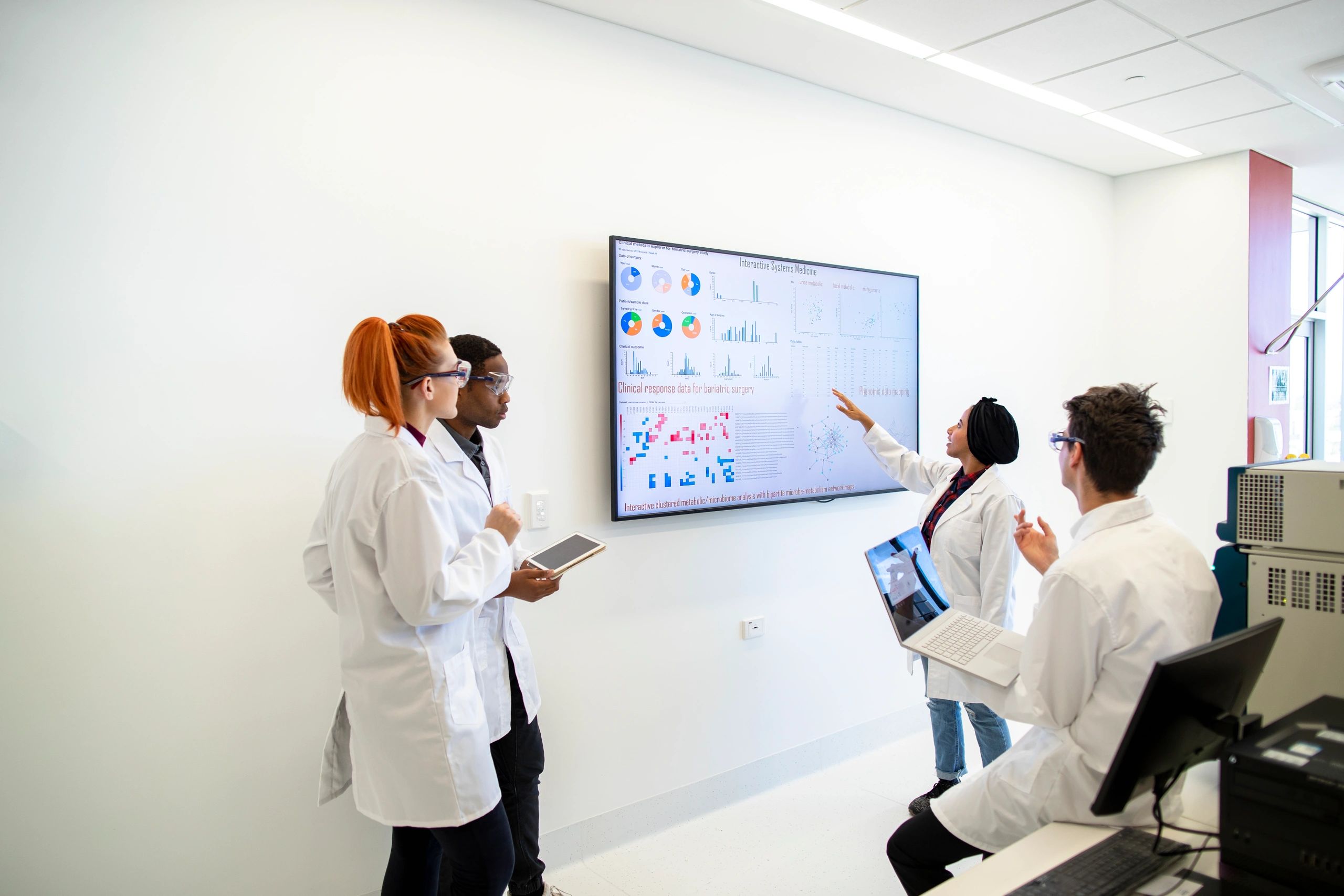 Professional research team gathered around a monitor reviewing data
